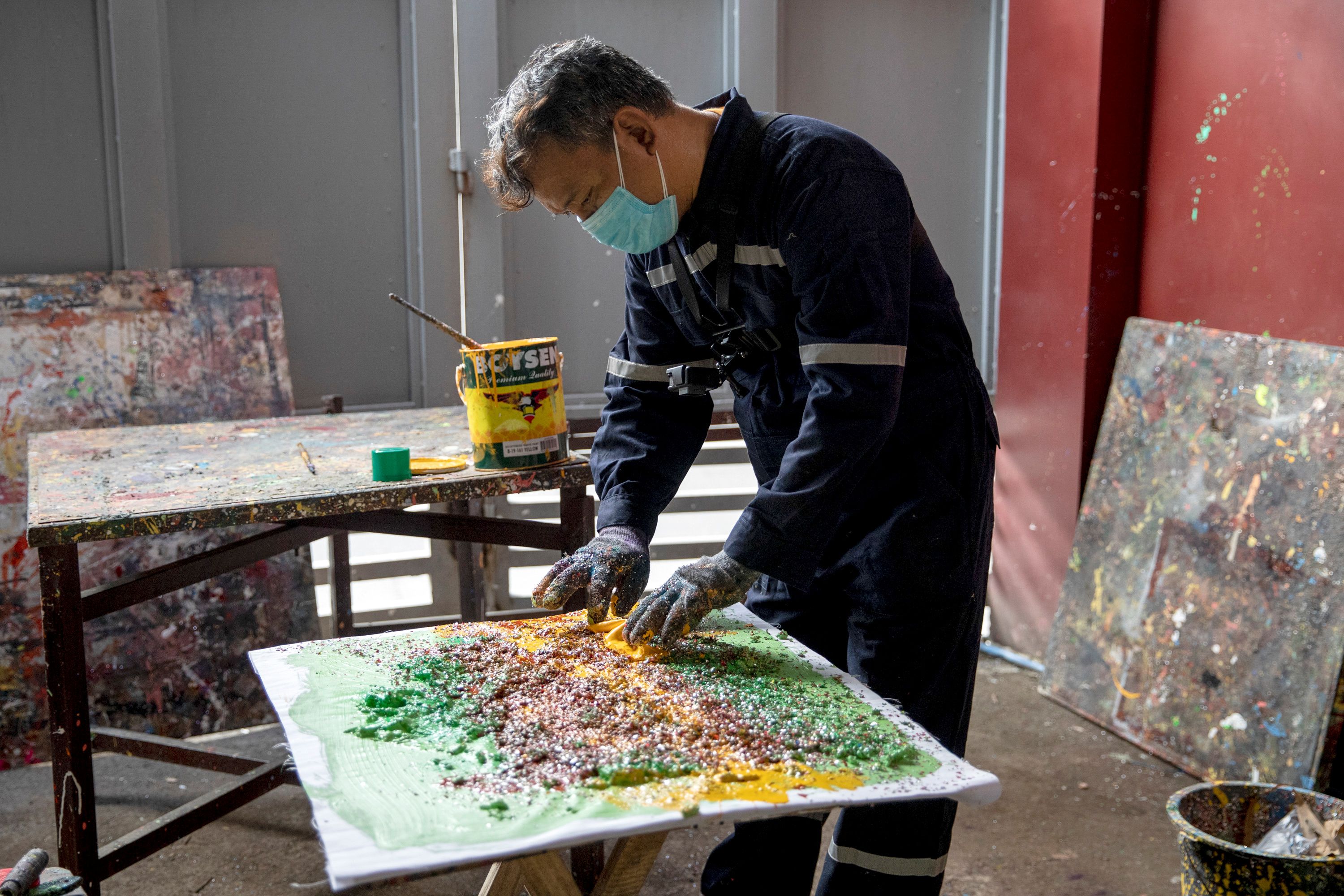 一个男人正在切比萨饼：菲律宾艺术家将旧的建筑材料改造成绘画